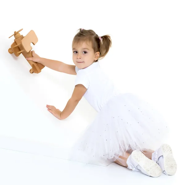Klein meisje speelt met een houten vliegtuig. — Stockfoto