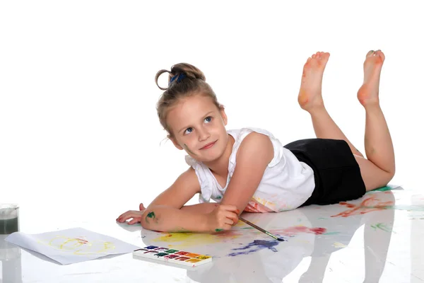 Uma menina pinta com tinta e pincel . — Fotografia de Stock