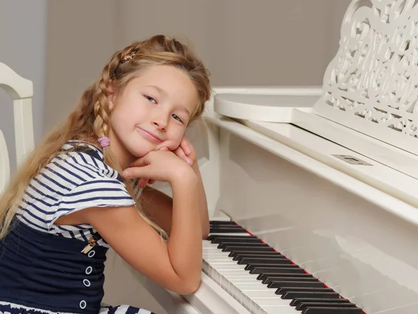 The girl is at the white grand piano. — Stock Photo, Image