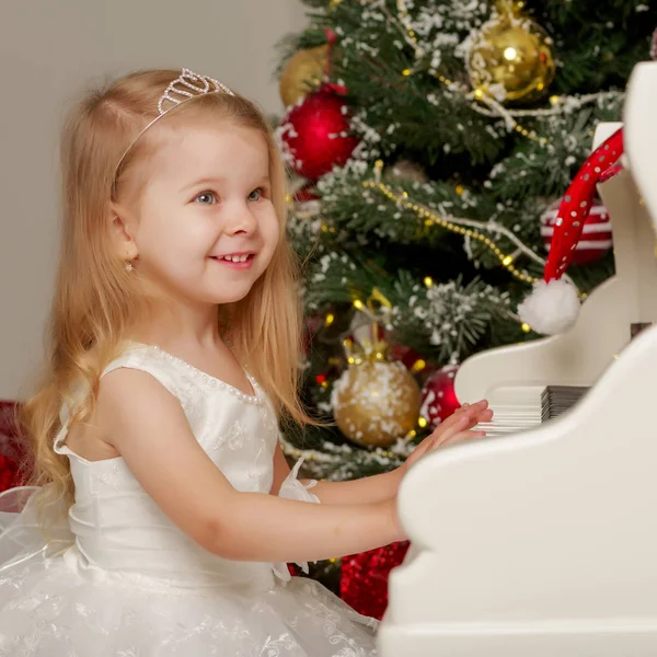 Bambina vicino al pianoforte e all'albero di Natale . — Foto Stock