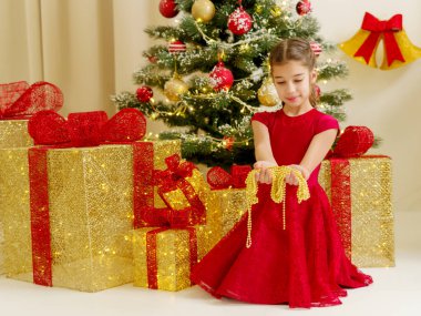Noel ağacı yanında küçük kız süsler tutuyor.