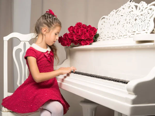 Flicka Skolflicka nära piano som ligger en bukett av blomma — Stockfoto