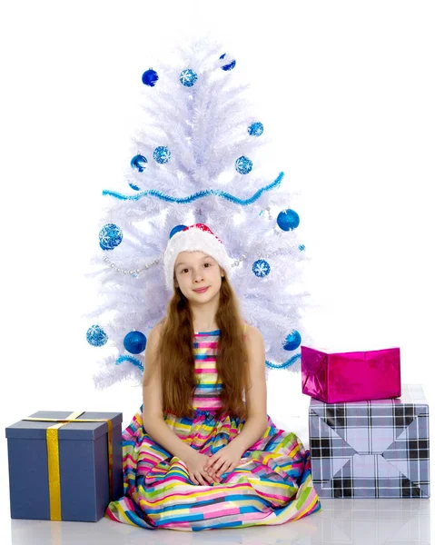 Una bambina con un regalo in un cappello di Babbo Natale . — Foto Stock