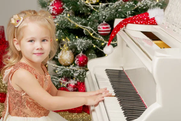 Bambina vicino al pianoforte e all'albero di Natale . — Foto Stock