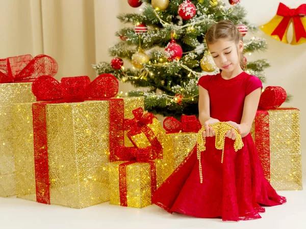 Noel ağacı yanında küçük kız süsler tutuyor. — Stok fotoğraf
