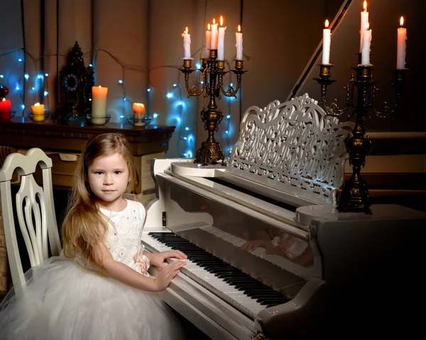 Niña toca el piano a la luz de las velas. —  Fotos de Stock