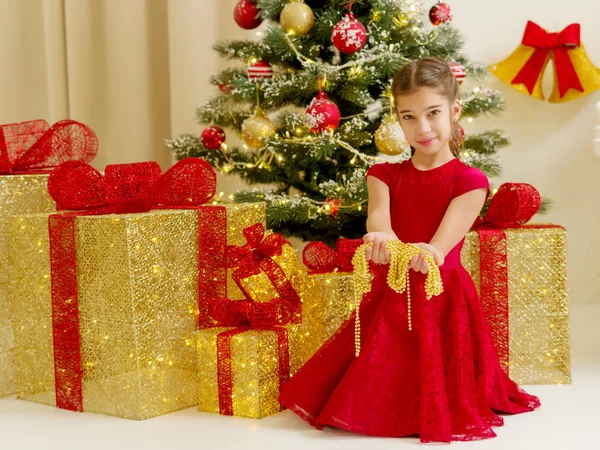 Liten flicka nära granen håller ornament. — Stockfoto