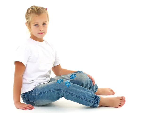 Uma menina está sentada no chão em uma camiseta branca limpa. — Fotografia de Stock