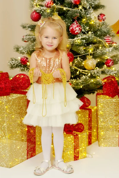 Μικρό κορίτσι κοντά το χριστουγεννιάτικο δέντρο είναι εκμετάλλευση στολίδια. — Φωτογραφία Αρχείου