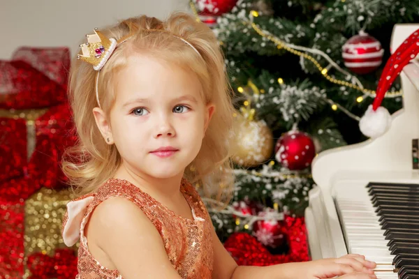 Uma Menina Bonita Sentada Perto Piano Branco Uma Árvore Natal — Fotografia de Stock
