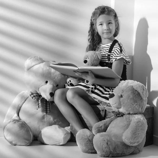 小女孩正在给泰迪熊读书. — 图库照片