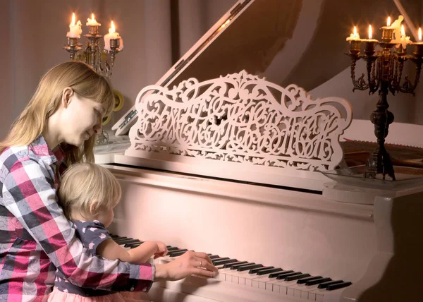 Мама с ребенком рядом с белым пианино — стоковое фото