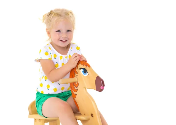 Girl swinging on a wooden horse. — Stock Photo, Image