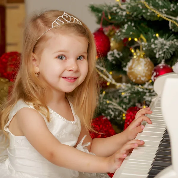 Bambina vicino al pianoforte e all'albero di Natale . — Foto Stock