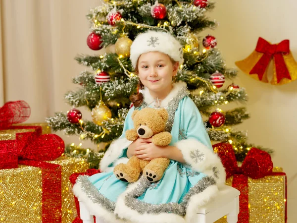 Menina no traje de donzela de neve com um urso de pelúcia perto de th — Fotografia de Stock