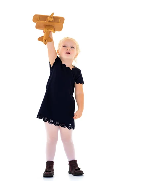 Menina está brincando com um avião de madeira. — Fotografia de Stock
