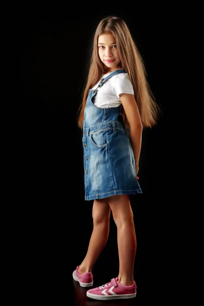 Kleines Mädchen in Jeanskleidung auf schwarzem Hintergrund. — Stockfoto