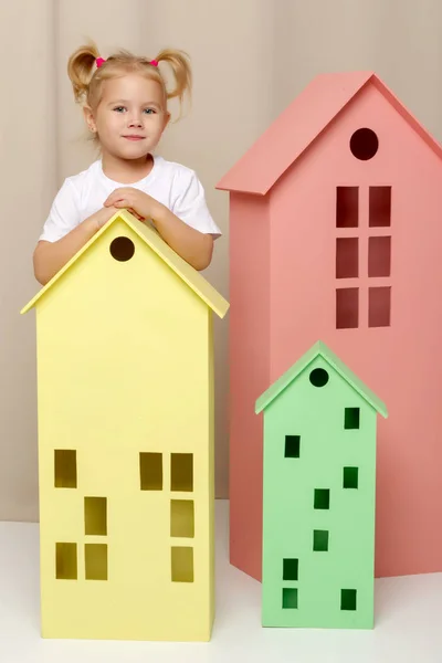 Маленька дівчинка дивиться з-за дерев'яного будинку іграшок . — стокове фото