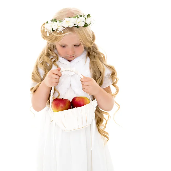 Liten flicka med en korg äpplen. — Stockfoto