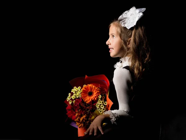 Menina com um buquê de flores em um fundo preto . — Fotografia de Stock
