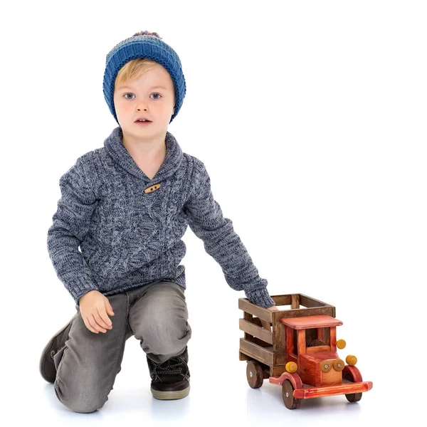 Kleine jongen speelt met een houten auto. — Stockfoto