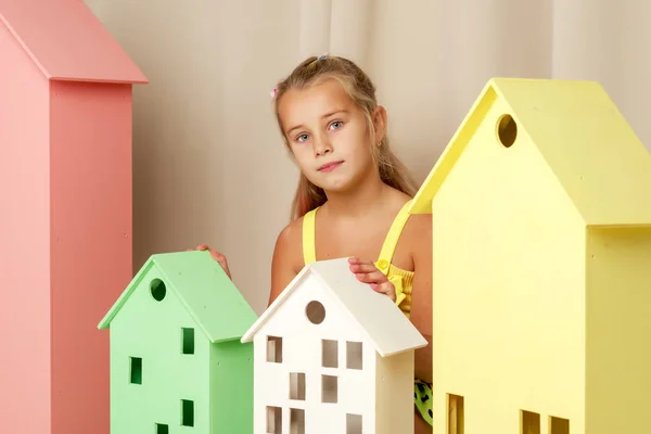 Ein kleines Mädchen blickt hinter einem Holzhaus hervor. — Stockfoto