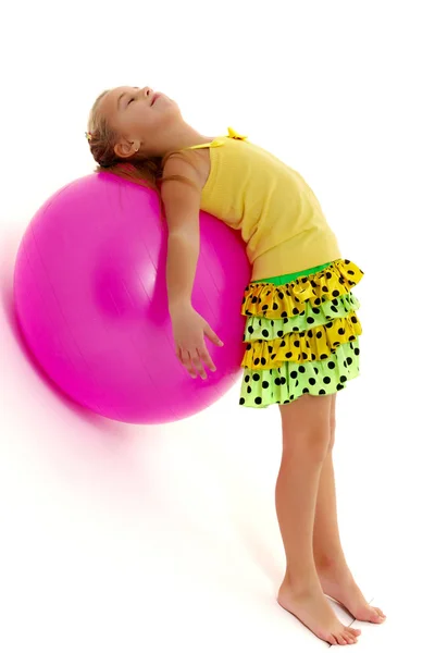 Küçük kız spor yapmak için büyük bir top üzerinde egzersiz yapıyor.. — Stok fotoğraf