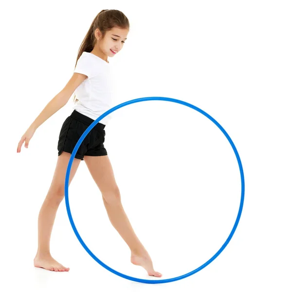 A little girl in a white T-shirt performs exercises with a hoop. — Stock Photo, Image