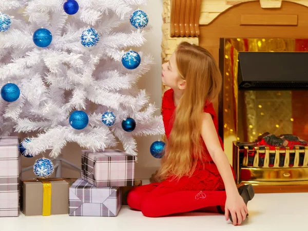 Uma menina está decorando uma árvore de Natal . — Fotografia de Stock