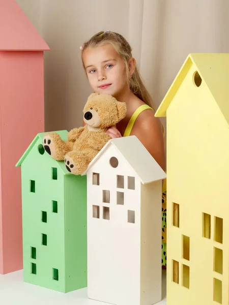 Küçük kız bir oyuncak ayı bir oyuncak ahşap evde ile oynarken. — Stok fotoğraf
