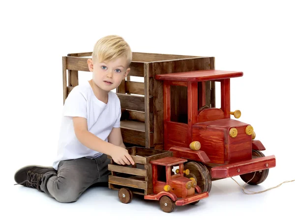 Kleine jongen speelt met een houten auto. — Stockfoto