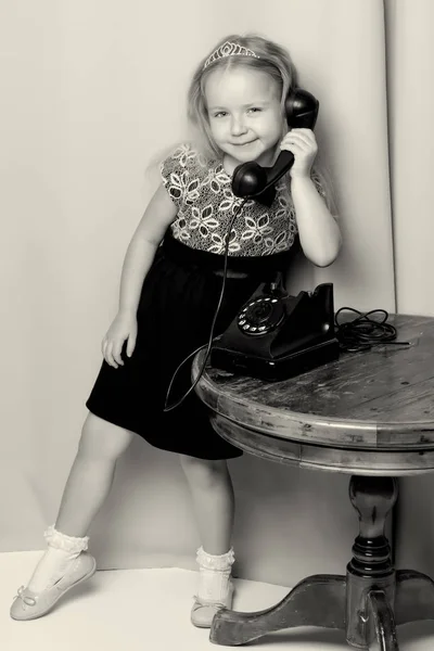 Uma menina está tocando no telefone antigo. — Fotografia de Stock