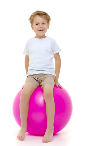 Le petit garçon sur le grand ballon est engagé dans la forme physique. T-sh blanc — Photo