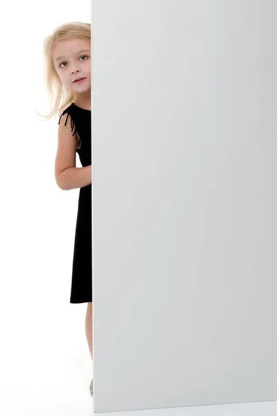 A little girl is looking from behind an empty banner. — Stock Photo, Image