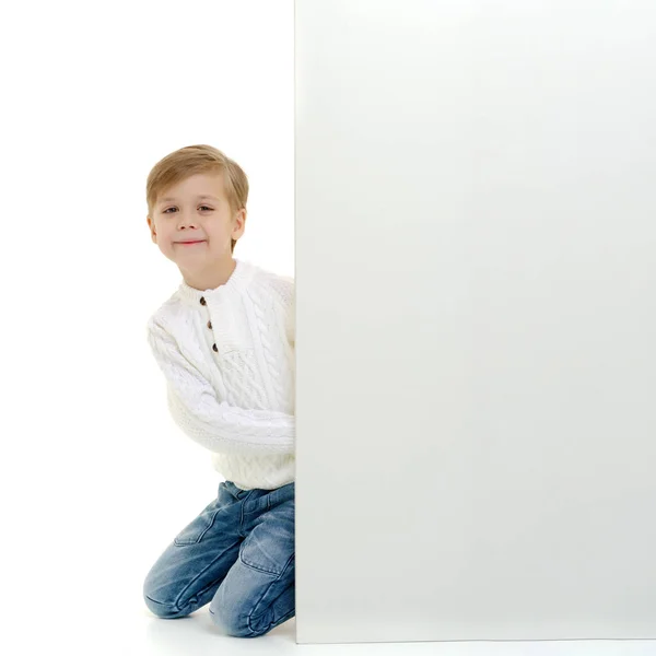 Mały chłopiec jest patrząc zza pusty transparent. — Zdjęcie stockowe