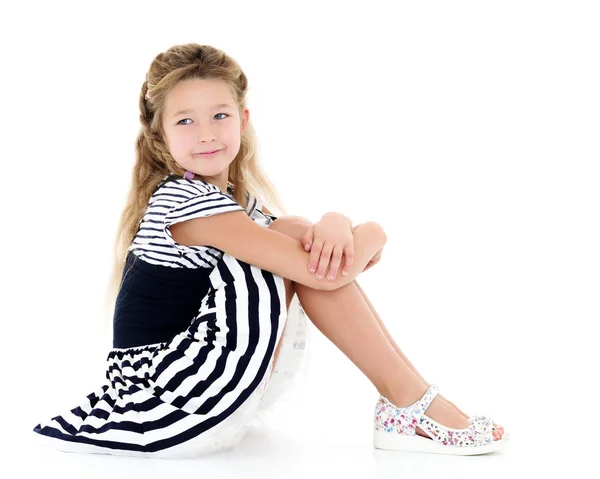 Petite fille assise sur le sol étreignant ses genoux avec sa main — Photo