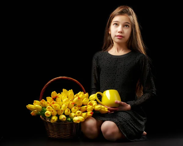 Menina com um buquê de tulipas em um fundo preto . — Fotografia de Stock