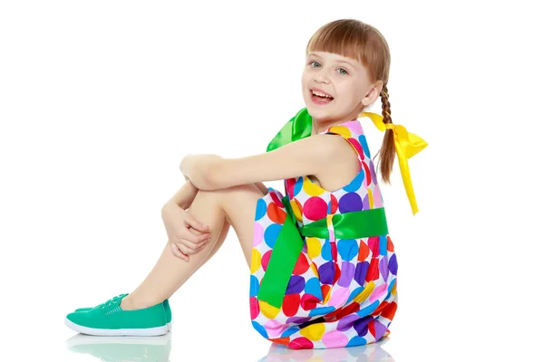 Ein kleines Mädchen in einem Kleid mit einem Muster aus buntem Zirkel — Stockfoto