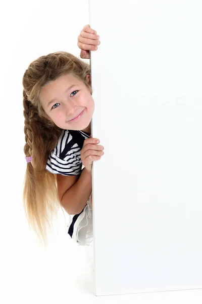 A little girl is looking from behind an empty banner. — Stock Photo, Image