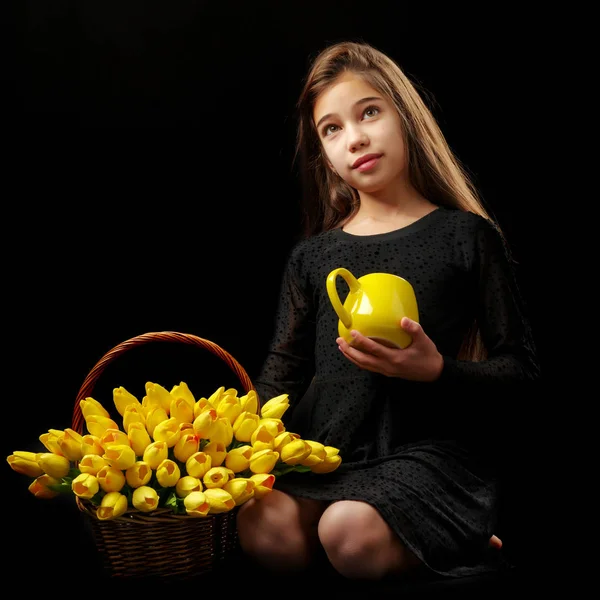 Little girl with a bouquet of tulips on a black background. — Stock Photo, Image