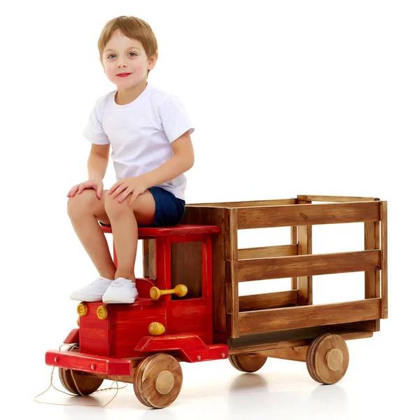 Liten pojke leker med en bil i trä. — Stockfoto