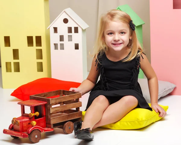 Menina está brincando com um carro de madeira . — Fotografia de Stock