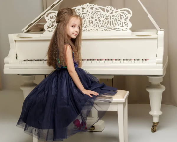 La chica está en el piano de cola blanco. —  Fotos de Stock