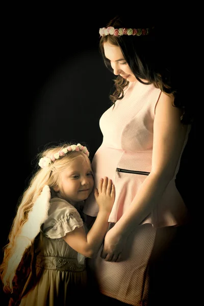 在天使形象的女孩拥抱她最大的 p 的肚子 — 图库照片