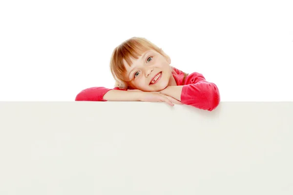 A little girl is looking from behind an empty banner. — Stock Photo, Image