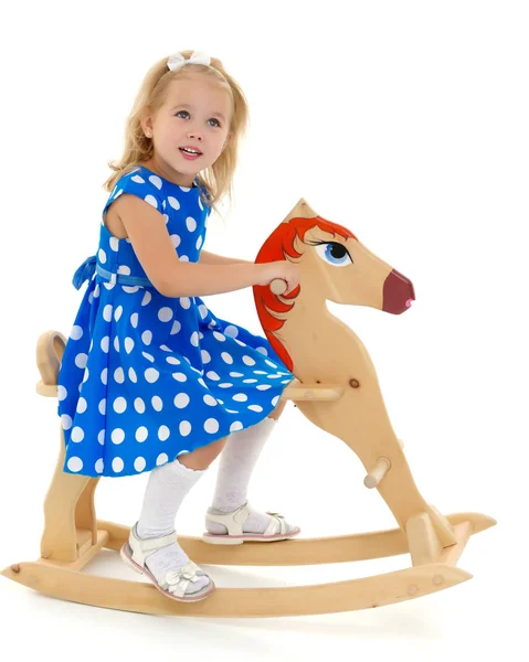 Menina balançando em um cavalo de madeira . — Fotografia de Stock