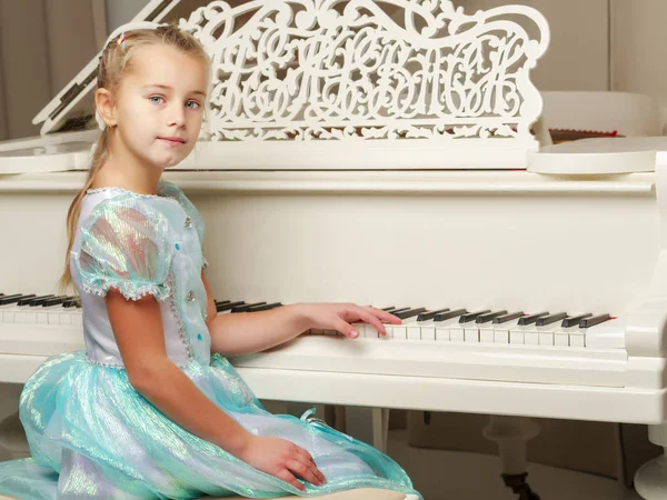 La ragazza è al pianoforte a coda bianco. — Foto Stock