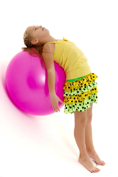 Klein meisje doet oefeningen op een grote bal voor fitness. — Stockfoto