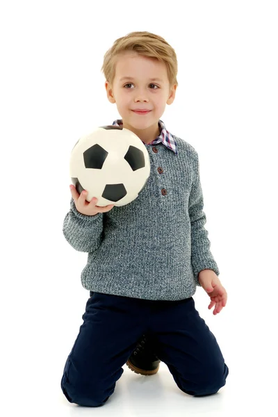 Menino está jogando com uma bola de futebol . — Fotografia de Stock