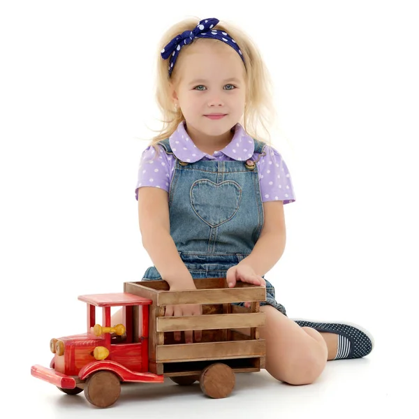 Dziewczynka bawi się z drewnianej samochód. — Zdjęcie stockowe